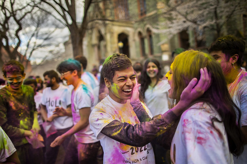 Students covered in colorful sawdust. Two students covering each other with colored sawdust.