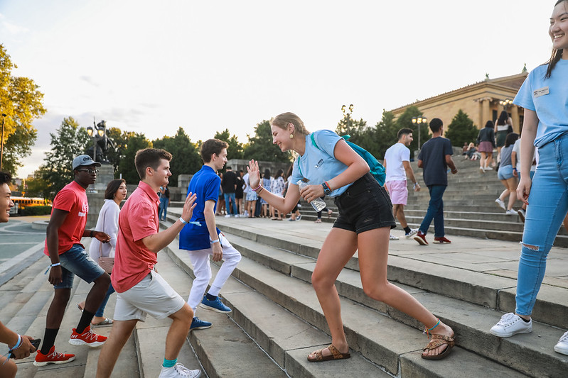 PHINS Student Leader high-fiving first year-student on the steps of the Philadelphia Museum of Art.