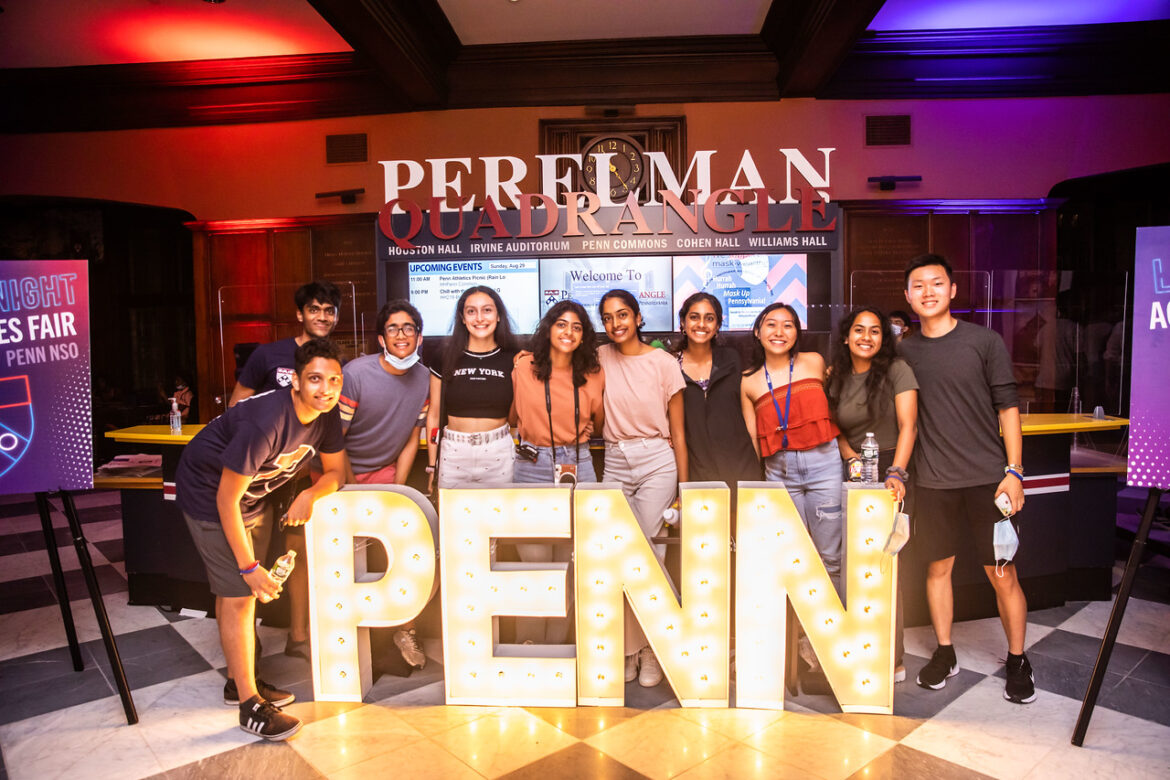ten penn students standing Infront of a lit up "PENN" sign 